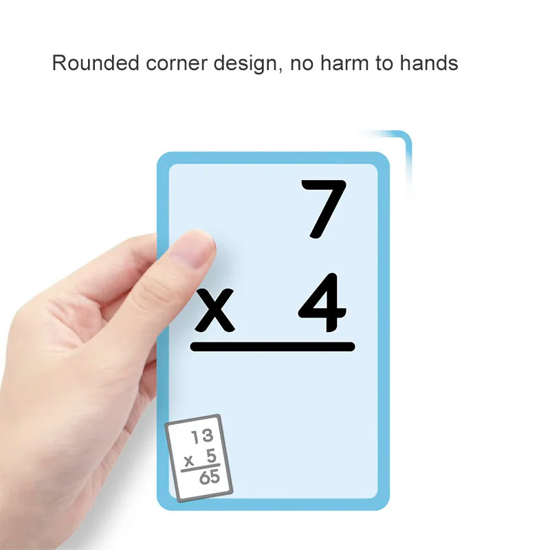 A hand holds a blue math practice card showing the multiplication problem 7 x 4 and another card showing 13 x 5/65.