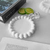 A white silicone bracelet is displayed next to a green citrus slice and clear crystal pieces on a white surface.