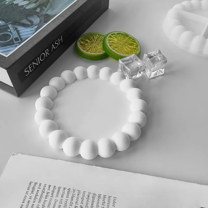 A white silicone bracelet is displayed next to a green citrus slice and clear crystal pieces on a white surface.