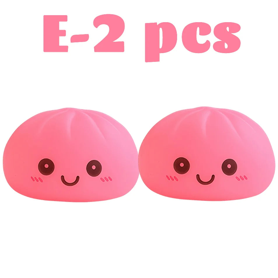 Dos juguetes suaves rosados con forma de dumplings y caras sonrientes