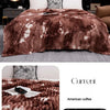 A brown flannel fleece throw blanket with a tie-dye pattern draped over a bed.