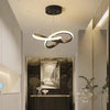 A modern interior scene featuring a curved gold LED pendant light fixture above a dark wooden console.