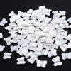 A pile of 100 white acrylic pearl spacer beads shaped like butterflies for jewelry making