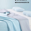 A light blue and gray ice silk cooling blanket is shown folded on a white surface with soft pillows nearby.