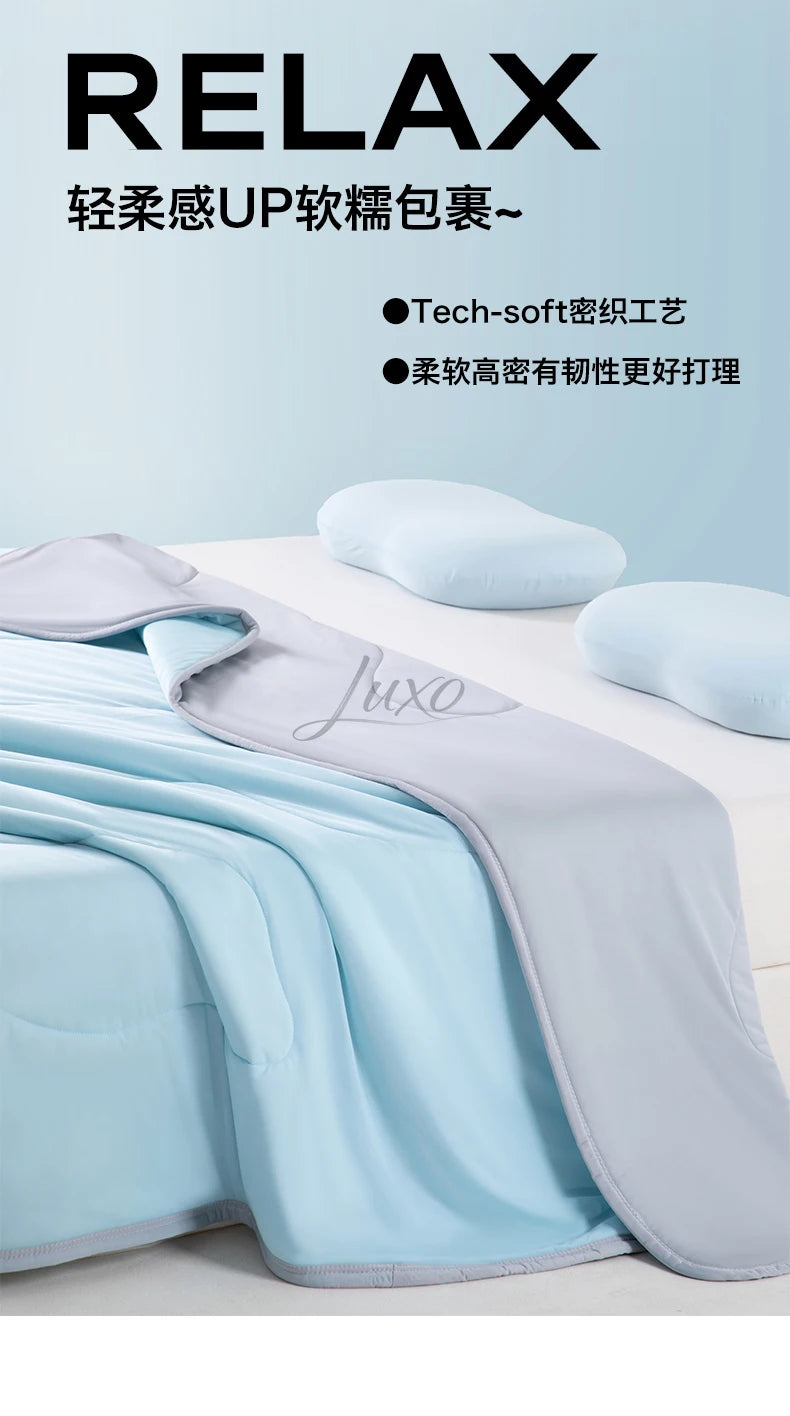 A light blue and gray ice silk cooling blanket is shown folded on a white surface with soft pillows nearby.
