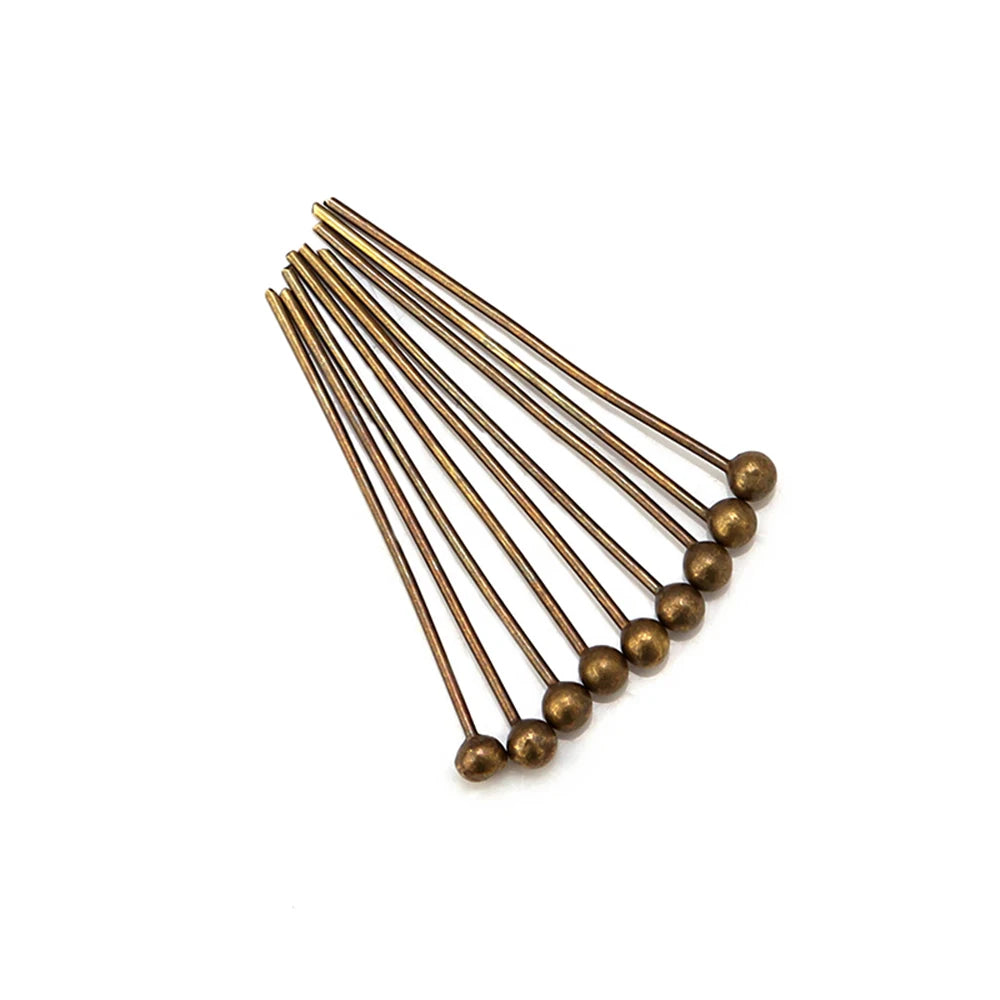 A set of gold-plated brass ball head pins for jewelry making arranged diagonally.