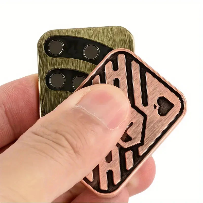 A hand holds a metal skull fidget slider stress relief toy with intricate carved patterns.