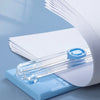 A close-up view of a portable manual paper cutter trimmer with a clear plastic blade and white paper, set against a light blu