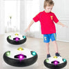 A boy is playing with a black and white multifunctional hover soccer ball in a brightly lit room.