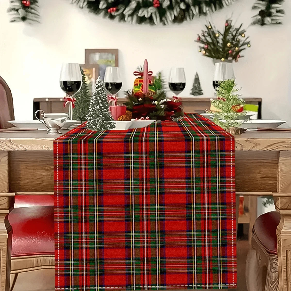 A red tartan Christmas table runner with green and black plaid pattern on a wooden table.