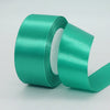 A roll of teal green satin ribbon used for gift wrapping or DIY crafts.