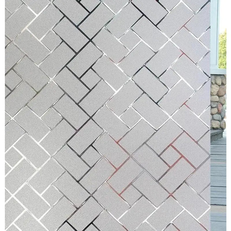 Close-up of a wall covered in gray and white brick pattern, showing a section of the decorative frosted window privacy film.