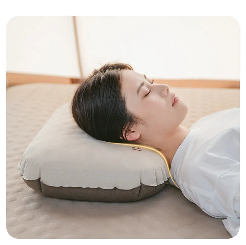 A person is resting their head on a beige foam inflatable camping pillow indoors.