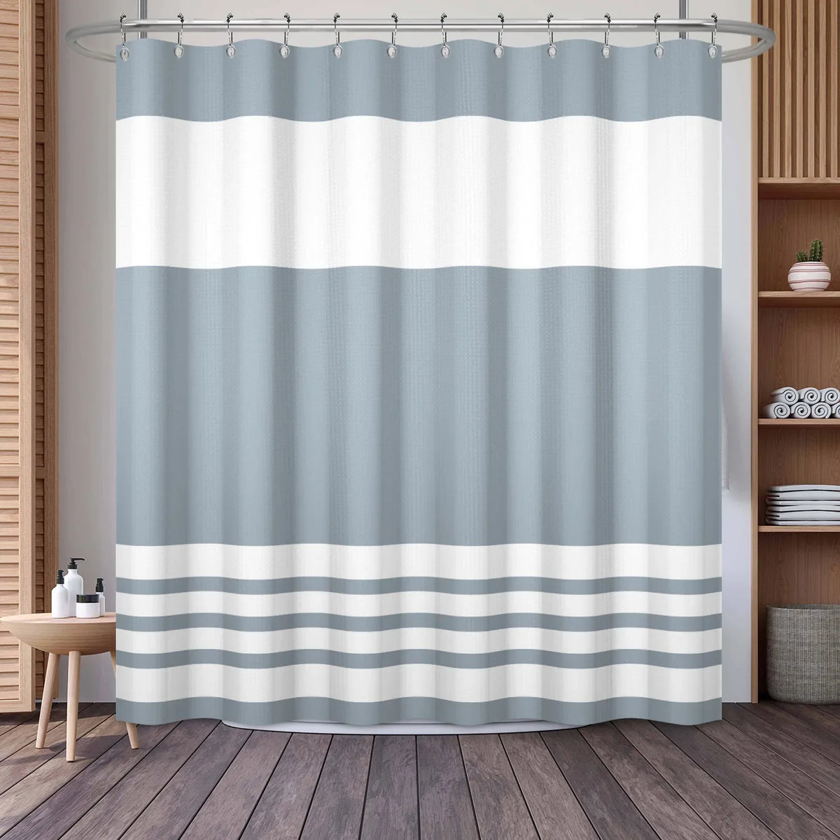 A shower curtain featuring a vertical geometric stripe pattern in shades of white and light blue gray.