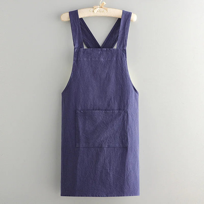 A dark indigo cotton kitchen apron hanging on a wooden hanger.