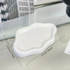 A white cloud-shaped jewelry tray with rounded edges is shown on a reflective surface.