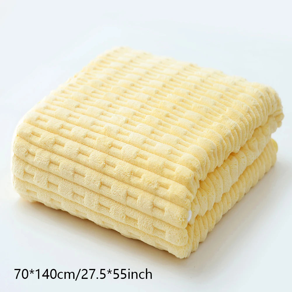 A stack of yellow coral velvet bath towels folded neatly on a white surface.