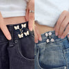 Close-up of hands adjusting no-sew adjustable waist tightener buttons on dark denim jeans.