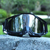 A pair of black retro motorcycle sunglasses with night vision lenses resting on a gray stone.