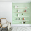 A light green wall niche displaying white floating shelves with books and decorative items.