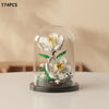 A clear glass display featuring a miniature white rose bouquet built from building blocks.