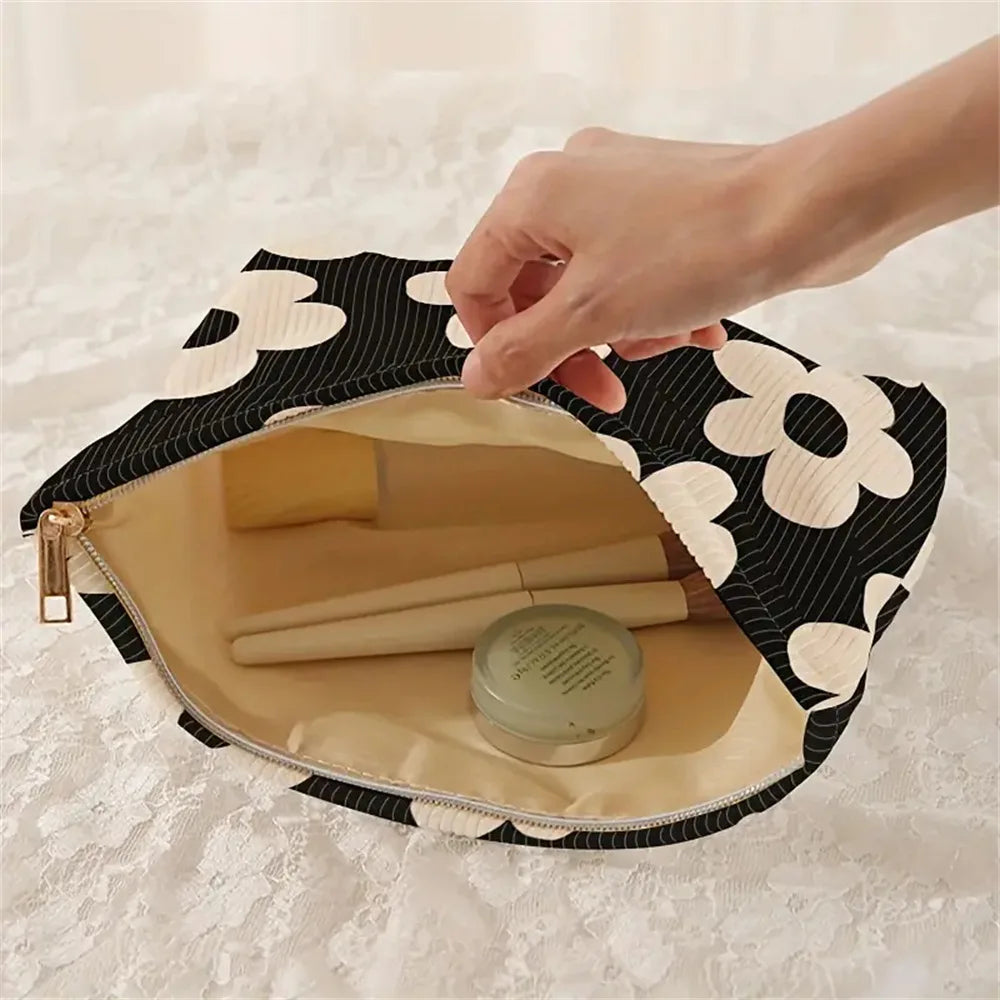 A hand is opening a floral patterned makeup bag with a secure zipper to reveal cosmetic products inside.