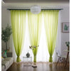 Light green sheer voile curtains hanging in a window with a dark rod pocket and white sheer fabric.
