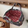 A dark floral patterned fabric storage basket with a woven handle is hanging on a wooden shelf.