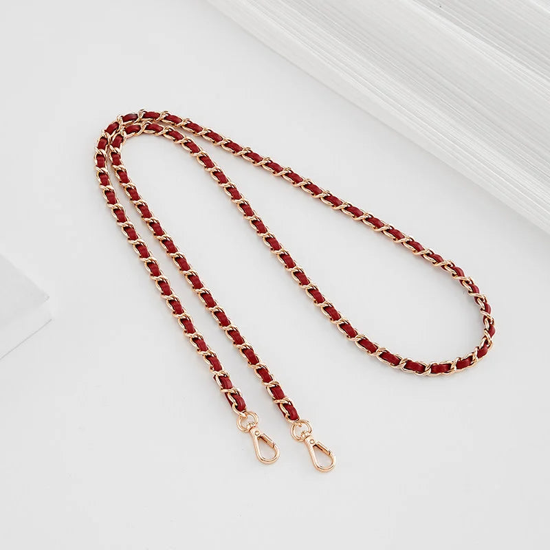 A close-up of a red beaded metal shoulder strap with gold-toned buckles.