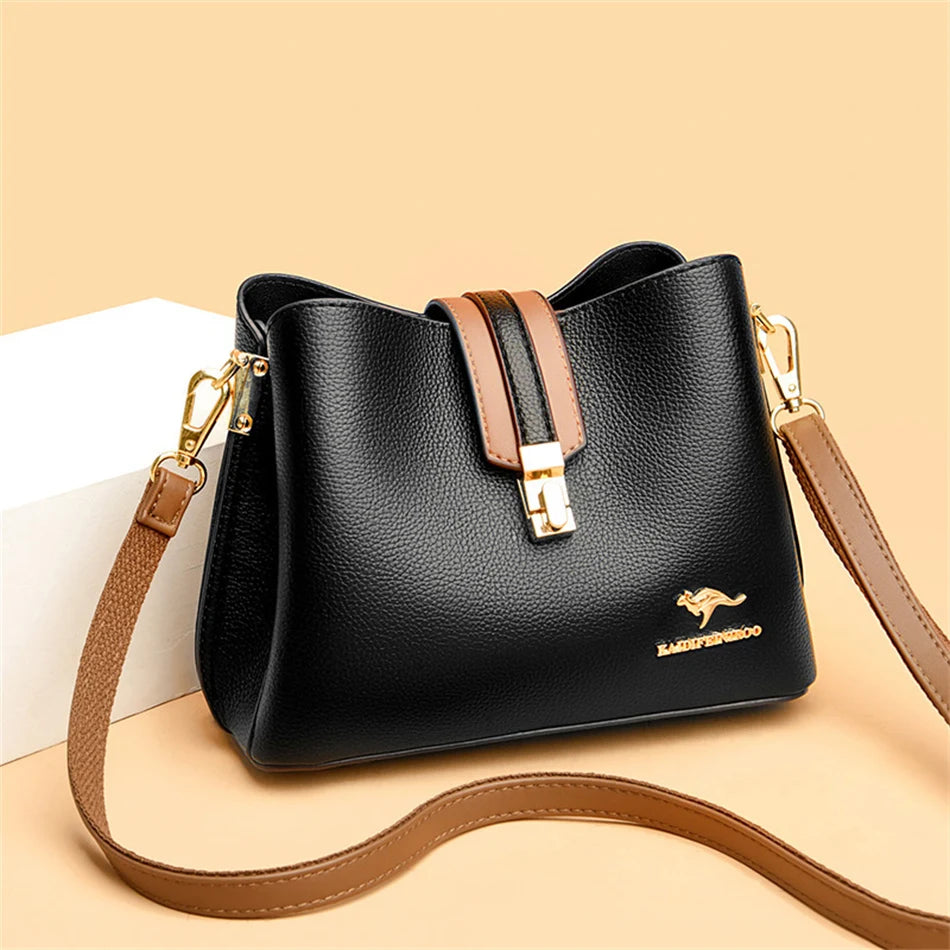 A black women's three-layer leather shoulder bag with a tan strap resting on a light background.