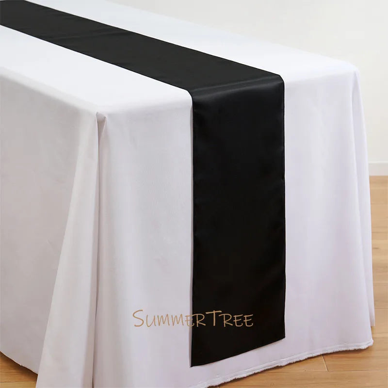 Elegant satin black table runner draped on a white tablecloth.