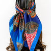 A vibrant blue and black leopard paisley square scarf tied around a dark brown wig.