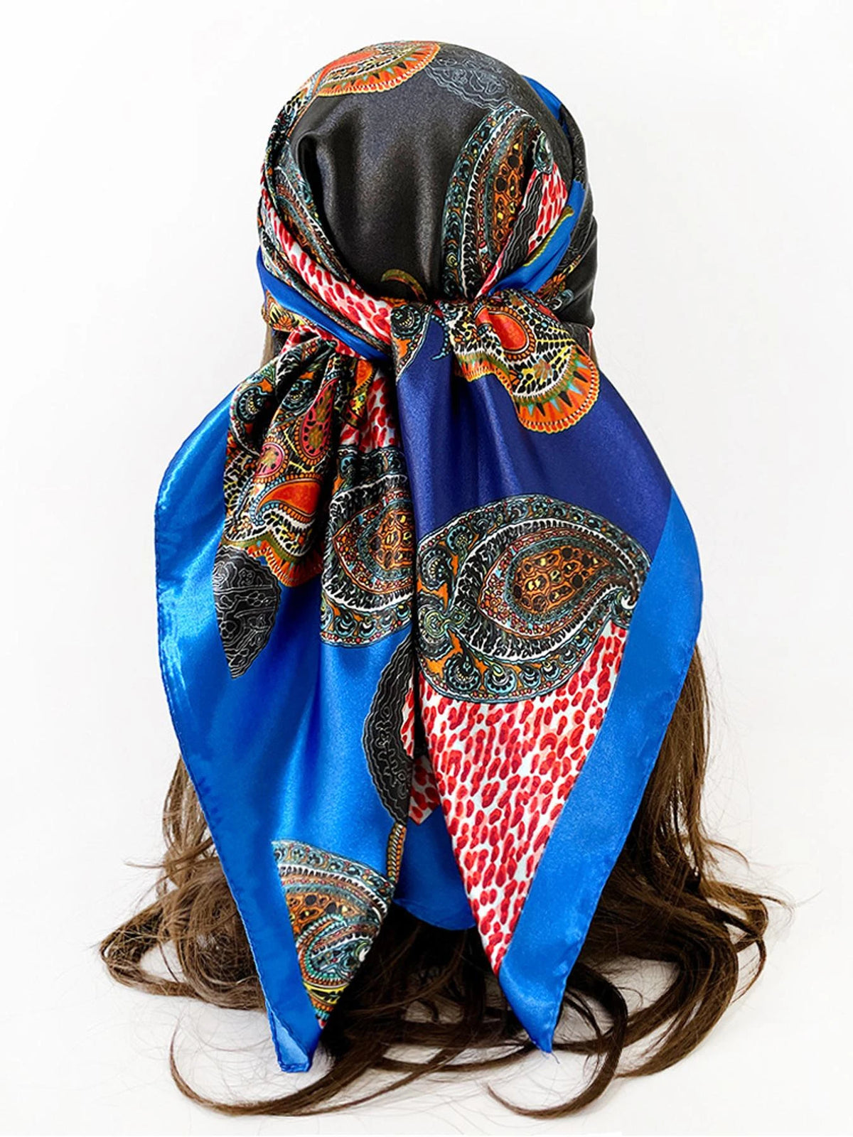 A vibrant blue and black leopard paisley square scarf tied around a dark brown wig.
