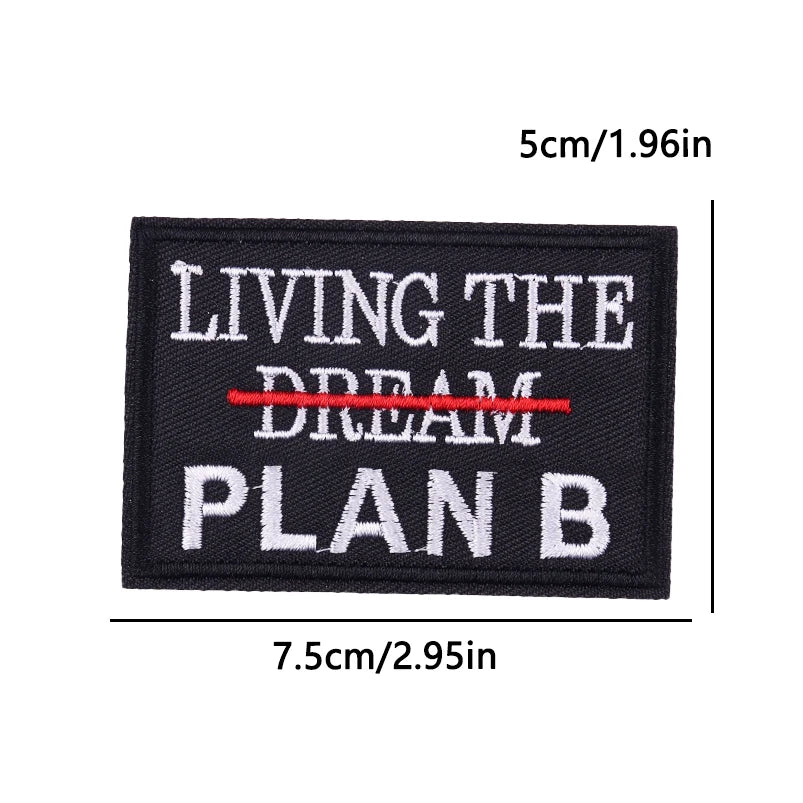 Black embroidered iron-on patch with white text reading LIVING THE DREAM PLAN B