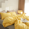 Yellow microfiber duvet cover set with pom tassels on a bed.