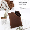 A brown canvas tote bag with a zipper is shown next to a small plant and a paper tag.