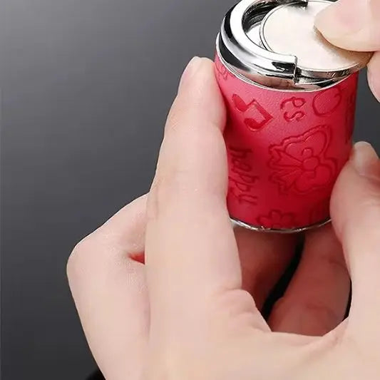 A hand is holding a red patterned metal coin tube keychain with a silver cap.