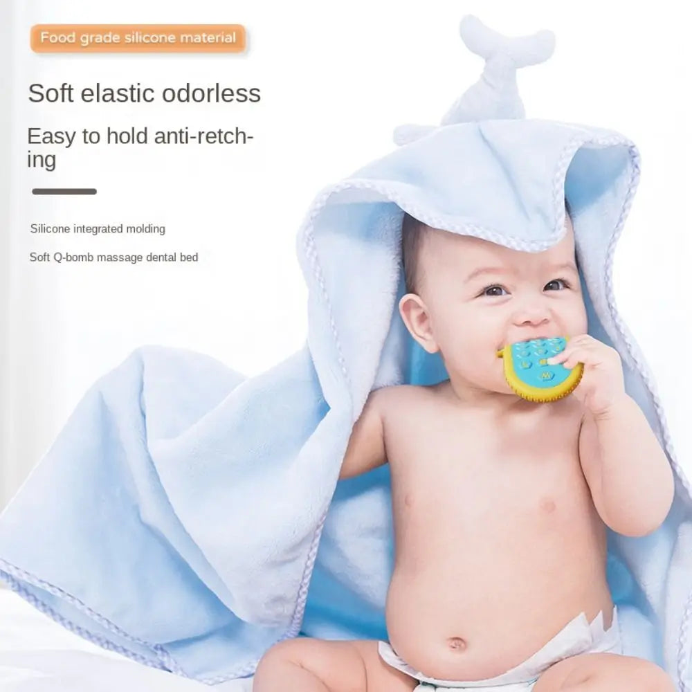 A baby is holding a silicone teether toy shaped like a gum relief while wrapped in a light blue towel.