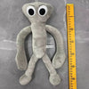 A gray plush toy resembling a bird with large white eyes and long limbs, shown next to a yellow ruler.