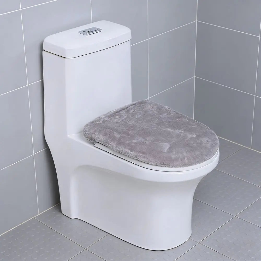 A white toilet with a soft gray flannel seat cover installed in a bathroom.