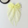 A pale yellow lace bow accessory for hair, featuring delicate floral patterns.