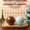 Two round stress balls, one chocolate brown and one light blue, are displayed on a wooden tray.