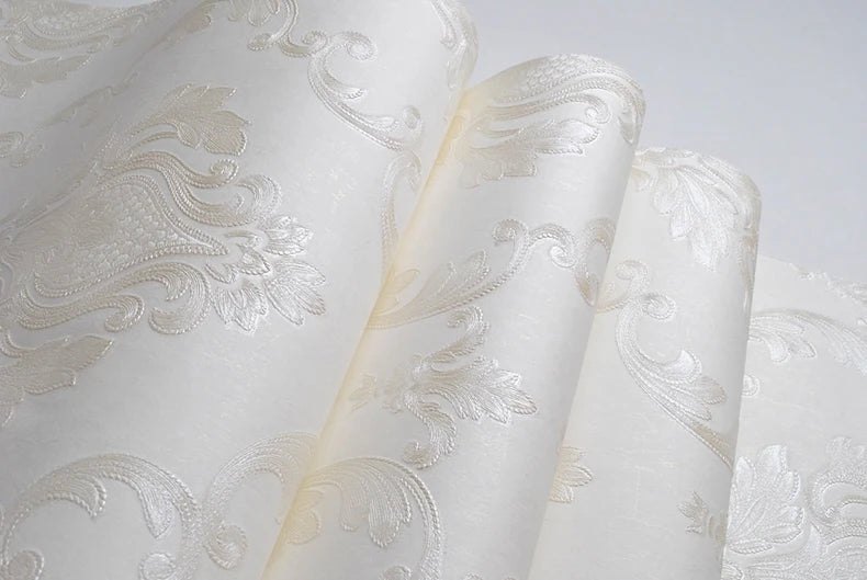 Roll of white embossed damask wallpaper featuring delicate floral scrollwork design.