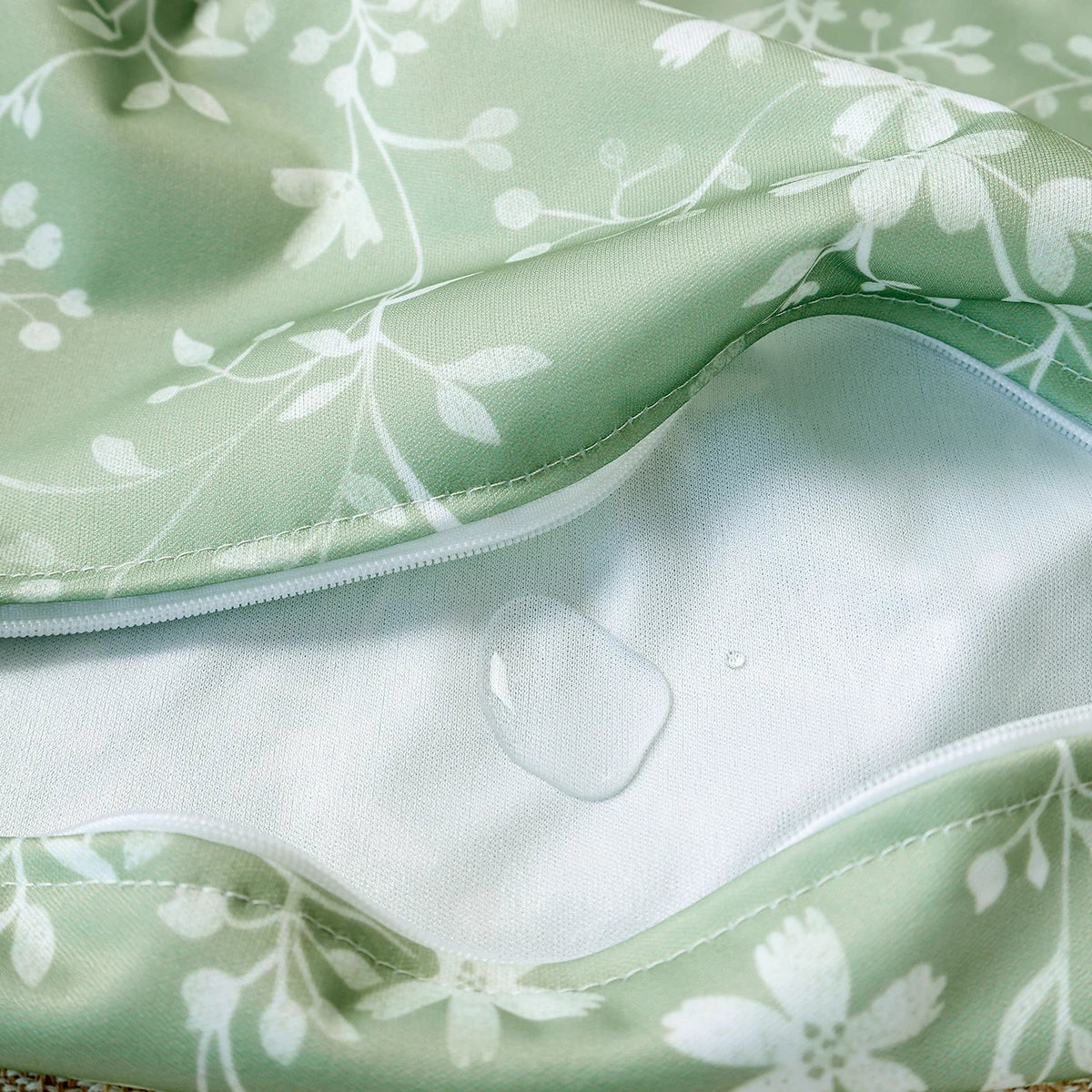 Light green reusable waterproof wet bag set fabric showing a white floral pattern and a clear plastic insert.
