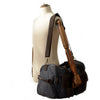 A tan mannequin displays a dark gray canvas duffel bag with brown leather straps and handles.
