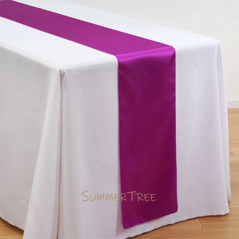 Elegant satin table runner in purple and white on a draped table.