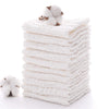 A stack of white soft natural cotton muslin baby washcloths with a fluffy cotton ball on top.