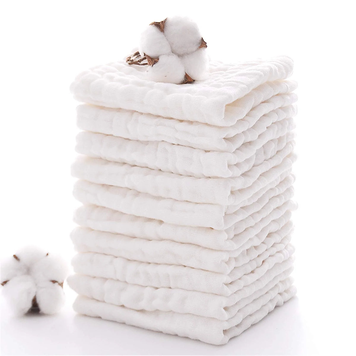 A stack of white soft natural cotton muslin baby washcloths with a fluffy cotton ball on top.