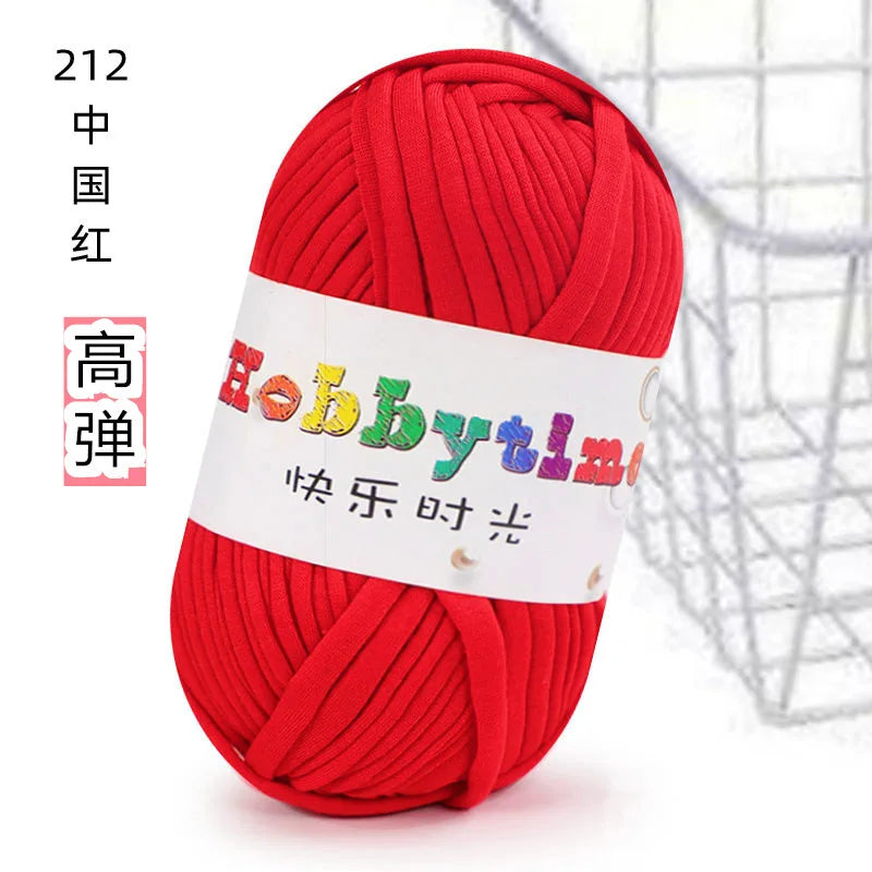 A ball of bright red soft T-shirt yarn for crochet and knitting is shown against a wire mesh background.