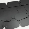 A collection of black aluminum stamping dog tags arranged on a white surface.